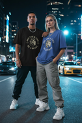 Hispanic male in black and white female in blue wearing Are You a Lion or a Snake Graphic Tee in city night setting